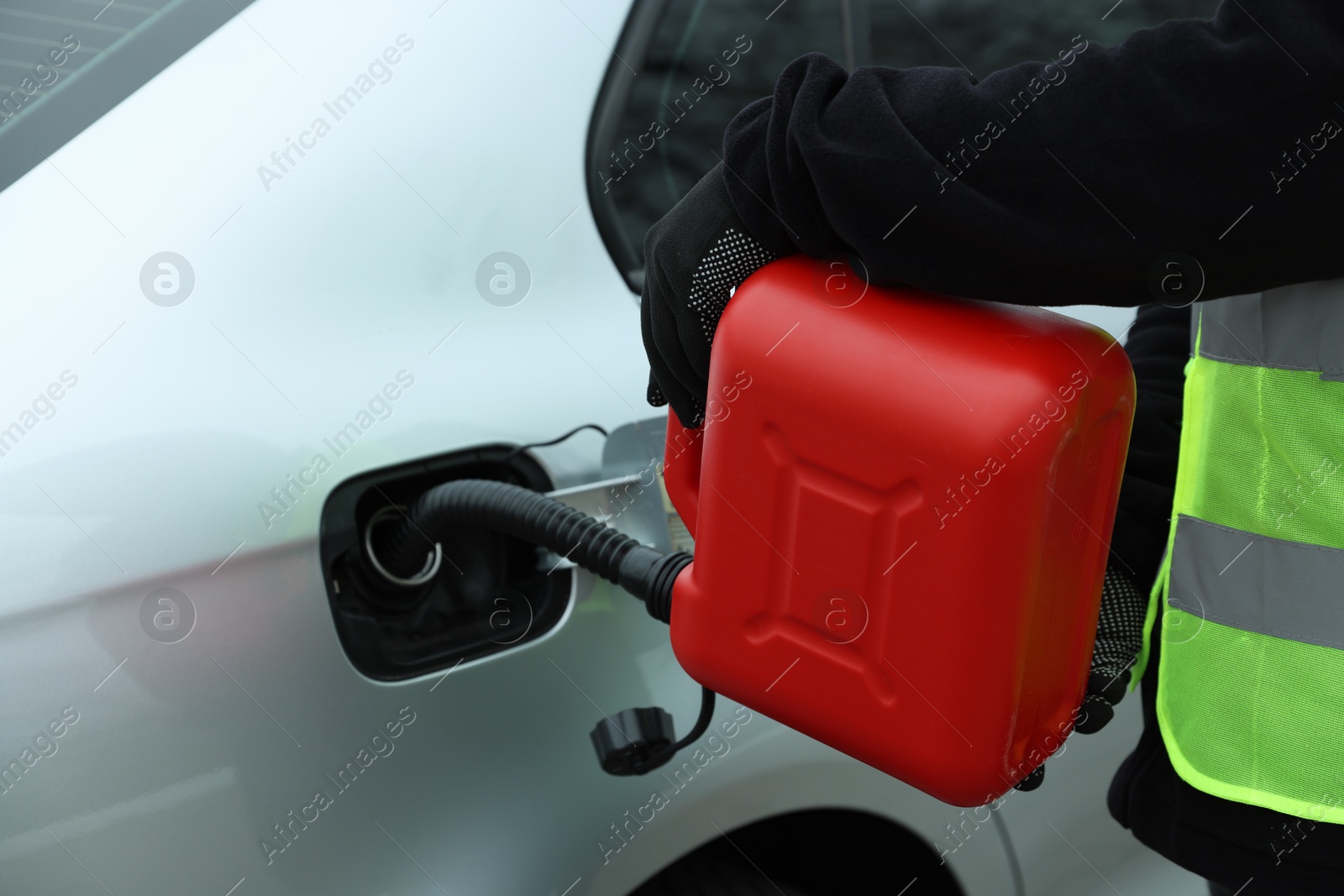 Photo of Man with canister refueling car outdoors, closeup