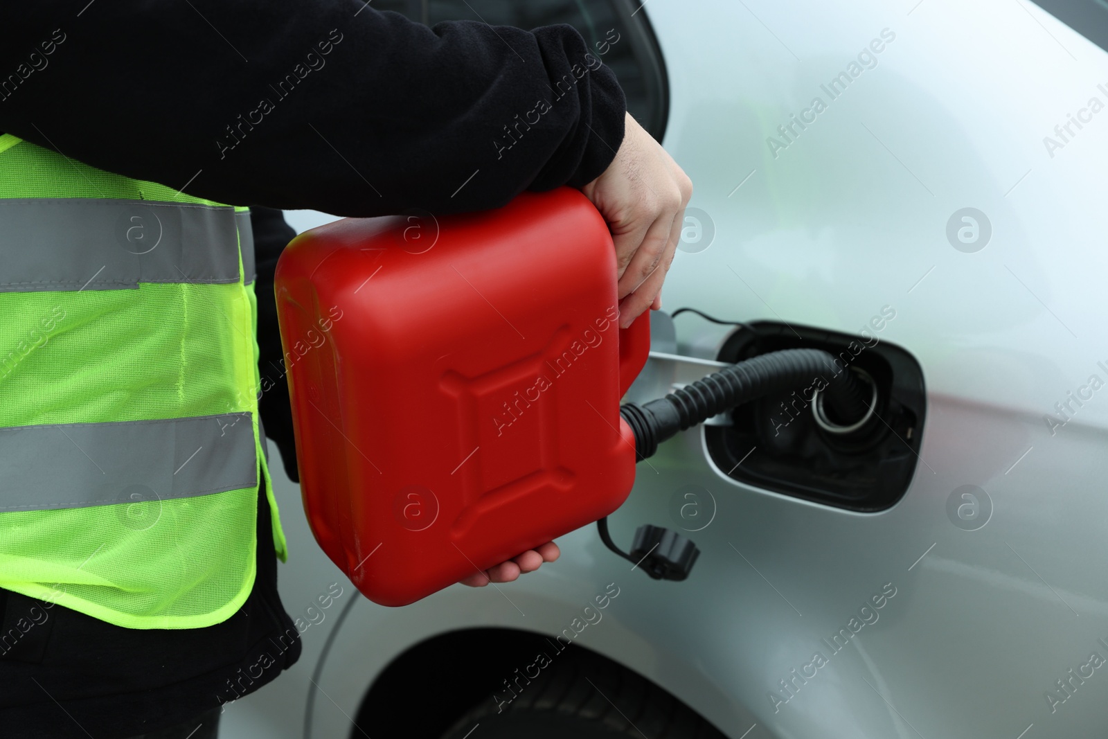 Photo of Man with canister refueling car outdoors, closeup