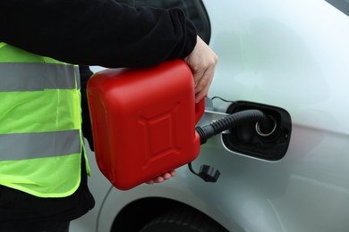 Photo of Man with canister refueling car outdoors, closeup