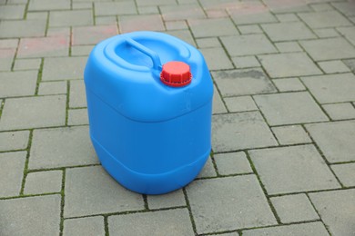 One blue plastic canister on pavement outdoors