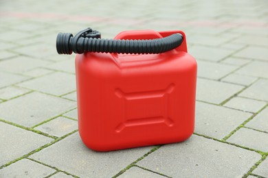 Photo of One red plastic canister with spout outdoors