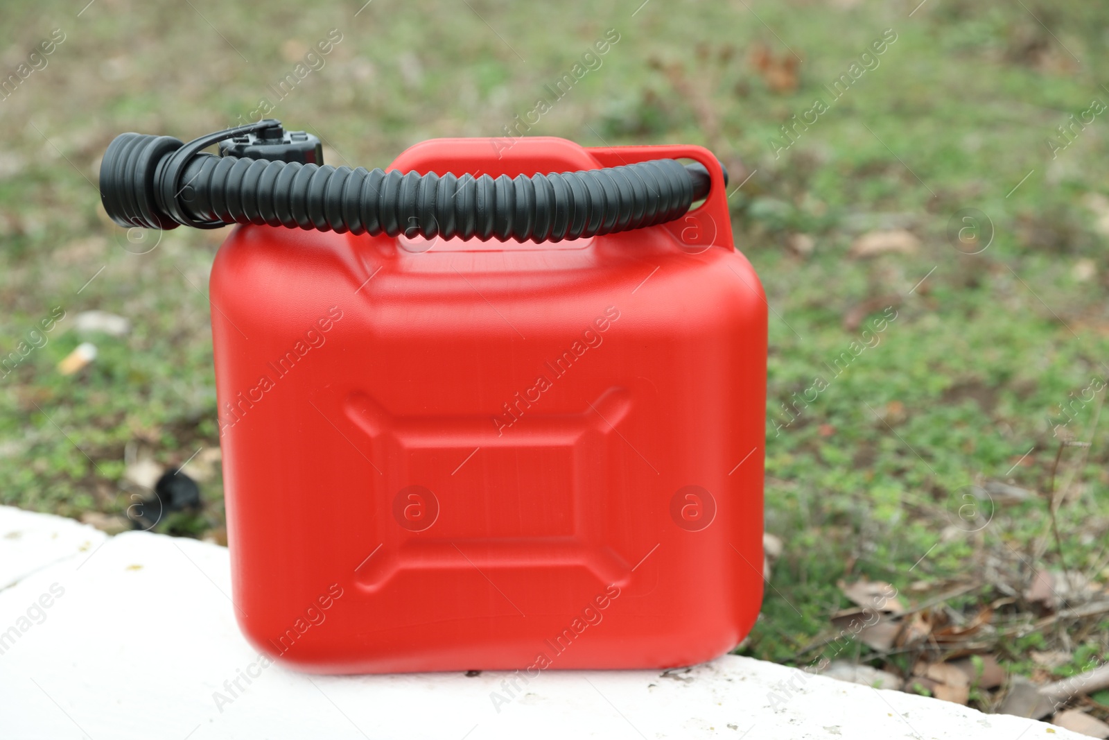 Photo of One red plastic canister with spout outdoors