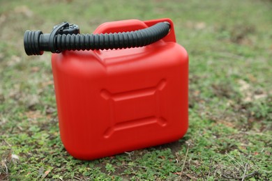 Red plastic canister with spout on green grass outdoors