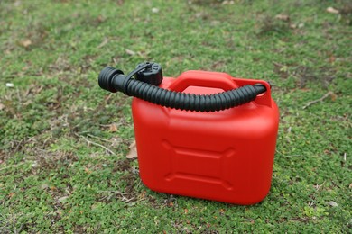 Red plastic canister with spout on green grass outdoors