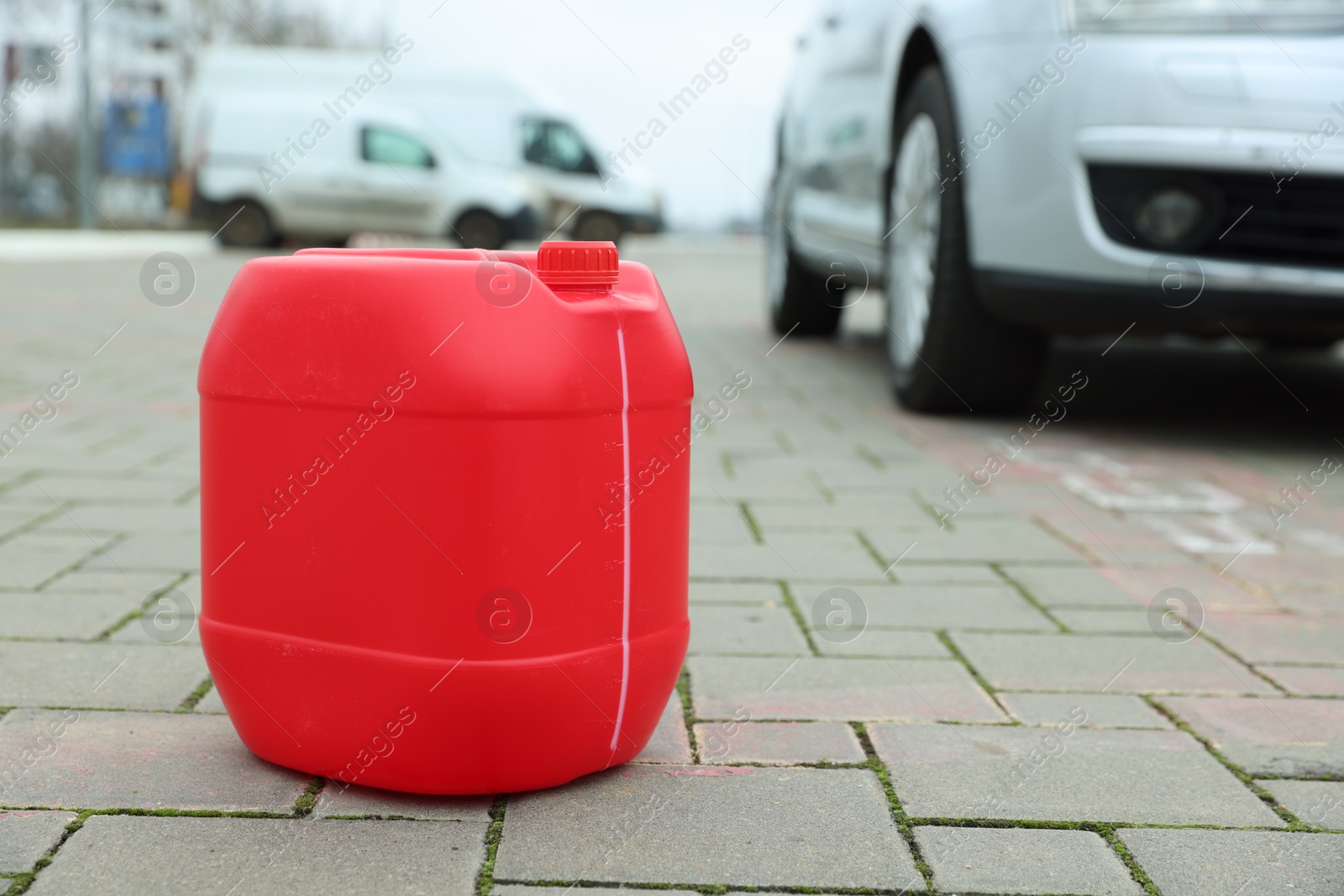 Photo of One red plastic canister on pavement outdoors