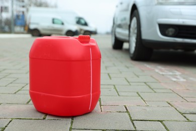 One red plastic canister on pavement outdoors