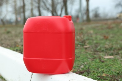 Photo of One red plastic canister on curb outdoors, space for text