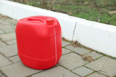 One red plastic canister on pavement outdoors