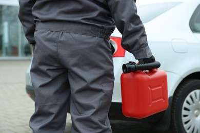 Photo of Man with canister near car outdoors, closeup