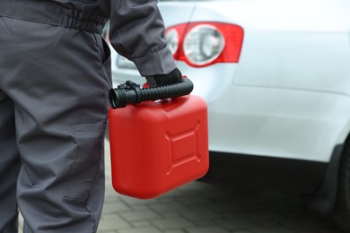 Photo of Man with canister near car outdoors, closeup