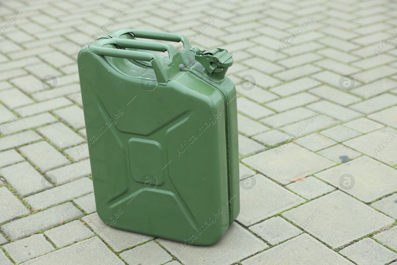 Photo of One khaki metal canister on pavement outdoors, space for text