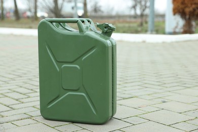 Photo of One khaki metal canister on pavement outdoors, space for text