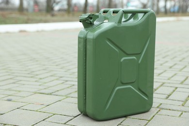 One khaki metal canister on pavement outdoors