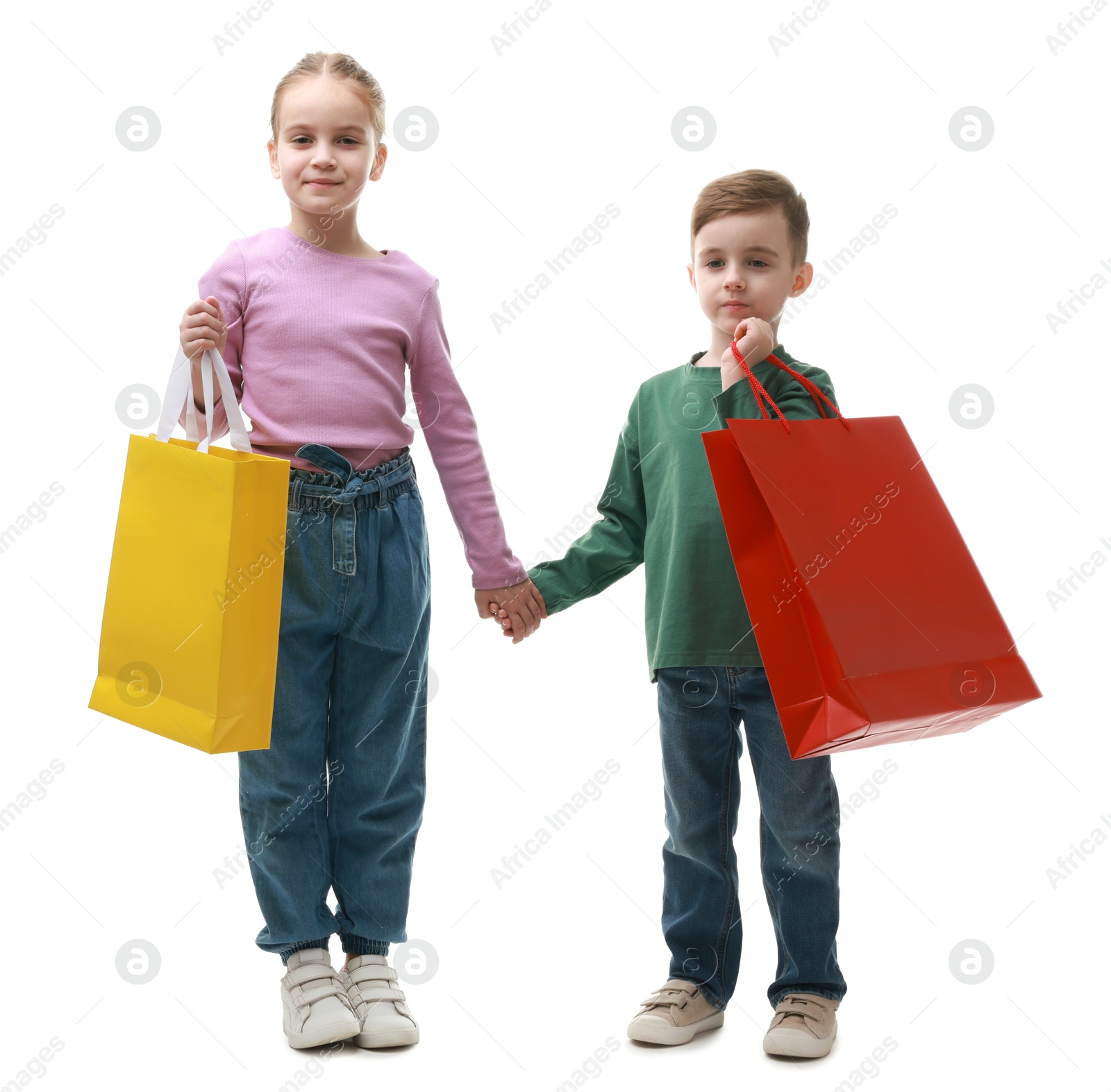 Photo of Cute little friends with shopping bags holding hands on white background