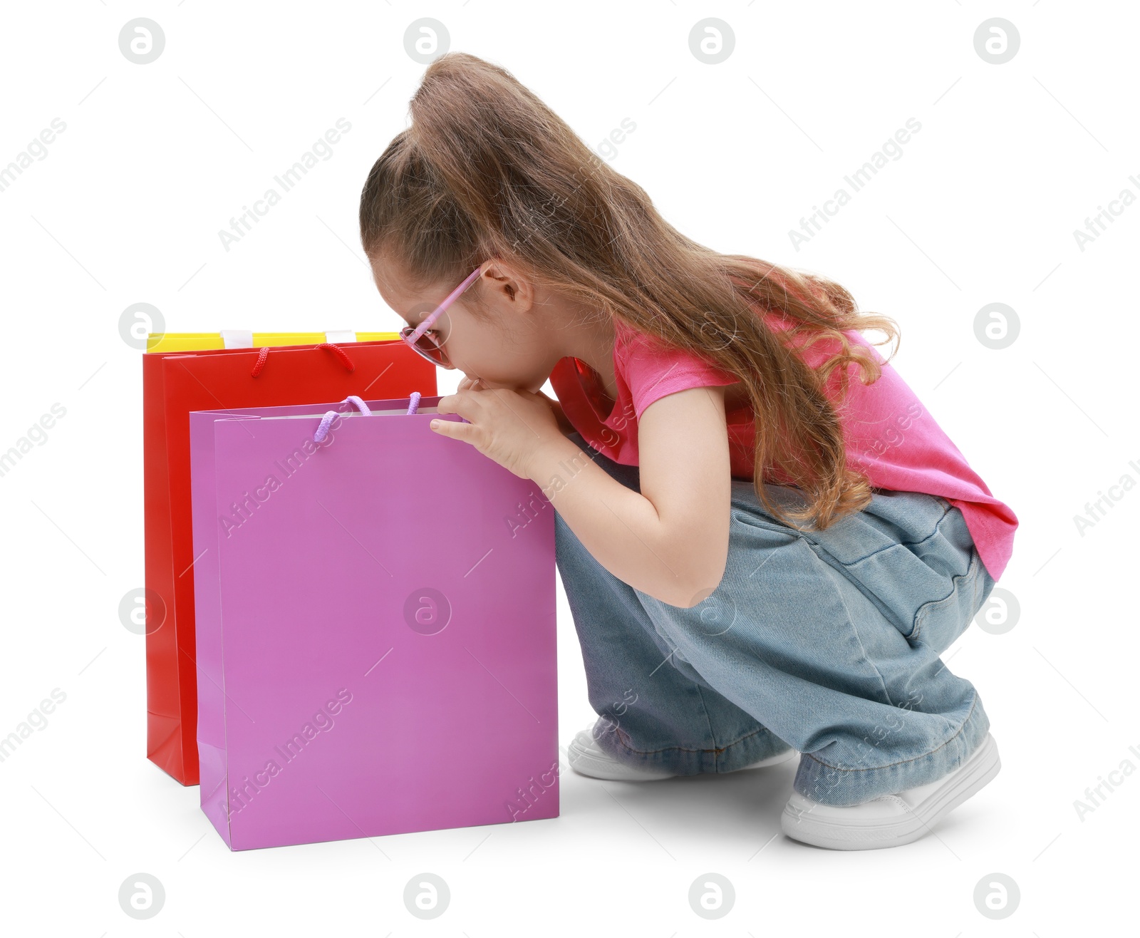 Photo of Cute little girl with shopping bags on white background