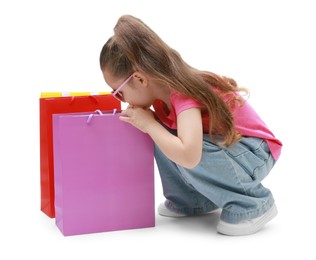 Photo of Cute little girl with shopping bags on white background