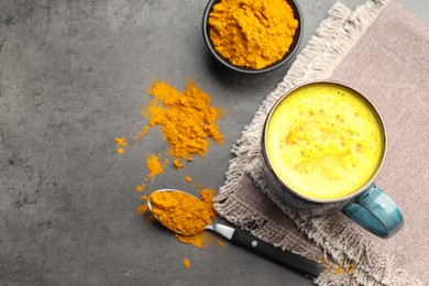 Photo of Tasty turmeric latte in cup and powder on grey table, flat lay. Space for text