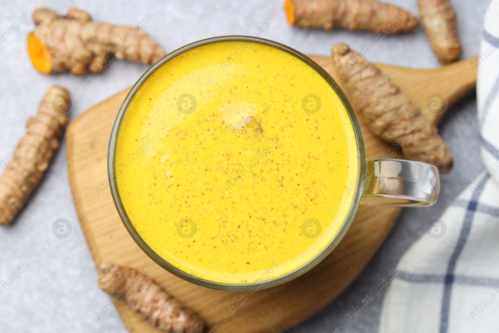 Photo of Tasty turmeric latte in cup and roots on grey table, flat lay