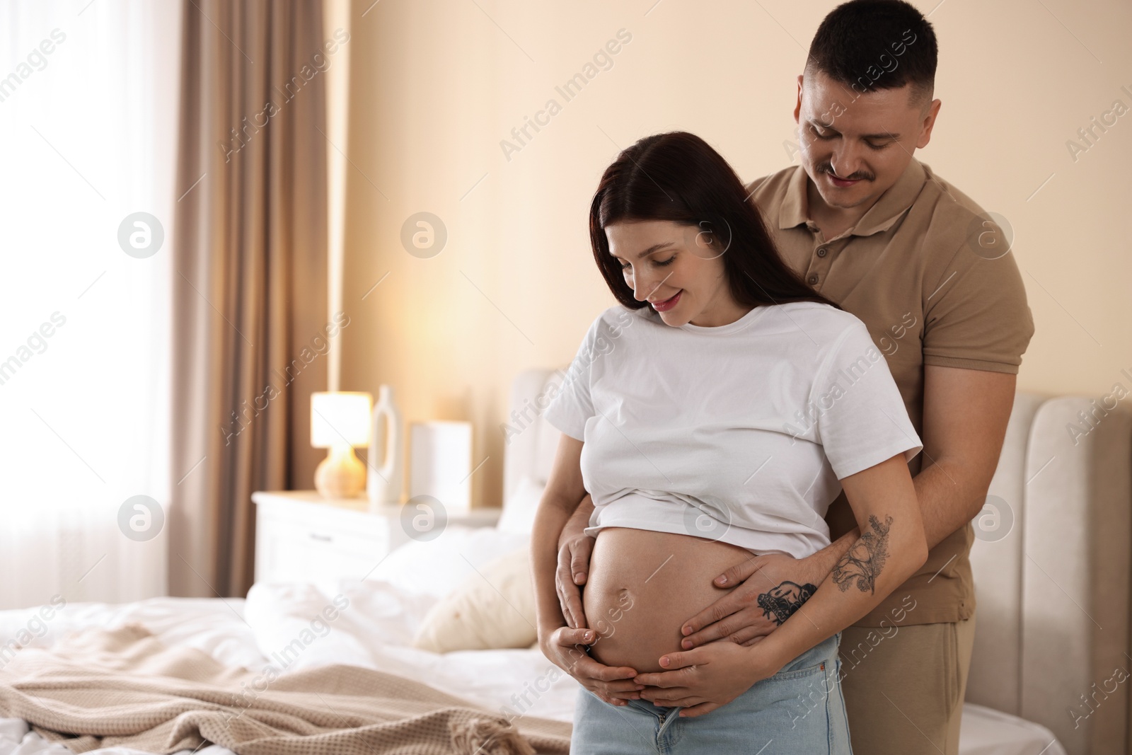 Photo of Pregnant woman and her husband at home, space for text