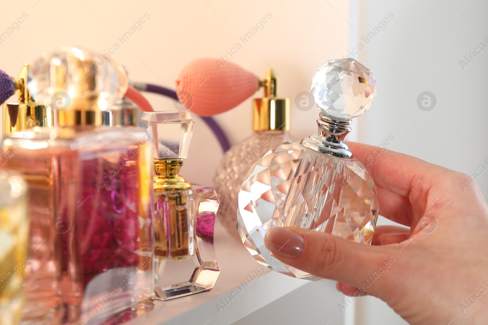 Photo of Woman taking bottle of perfume from shelf in store, closeup