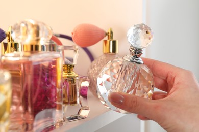 Photo of Woman taking bottle of perfume from shelf in store, closeup