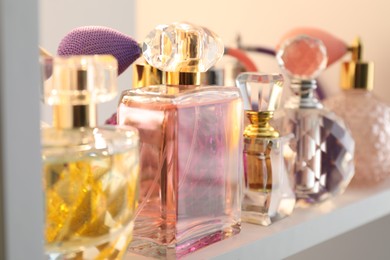 Photo of Different bottles of luxury perfume on shelf in store, closeup