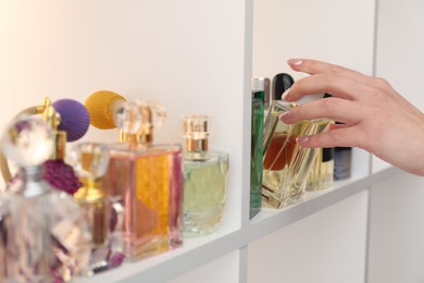 Photo of Woman taking bottle of perfume from shelf in store, closeup