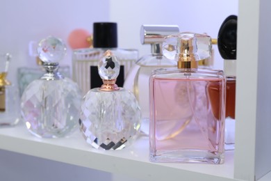 Photo of Different bottles of luxury perfume on shelf in store, closeup