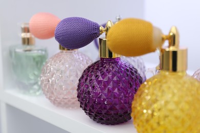 Photo of Different bottles of luxury perfume on shelf in store, closeup