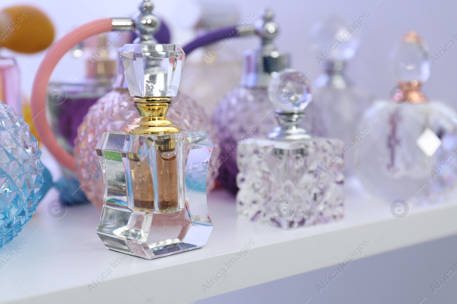 Photo of Different bottles of luxury perfume on shelf in store, closeup