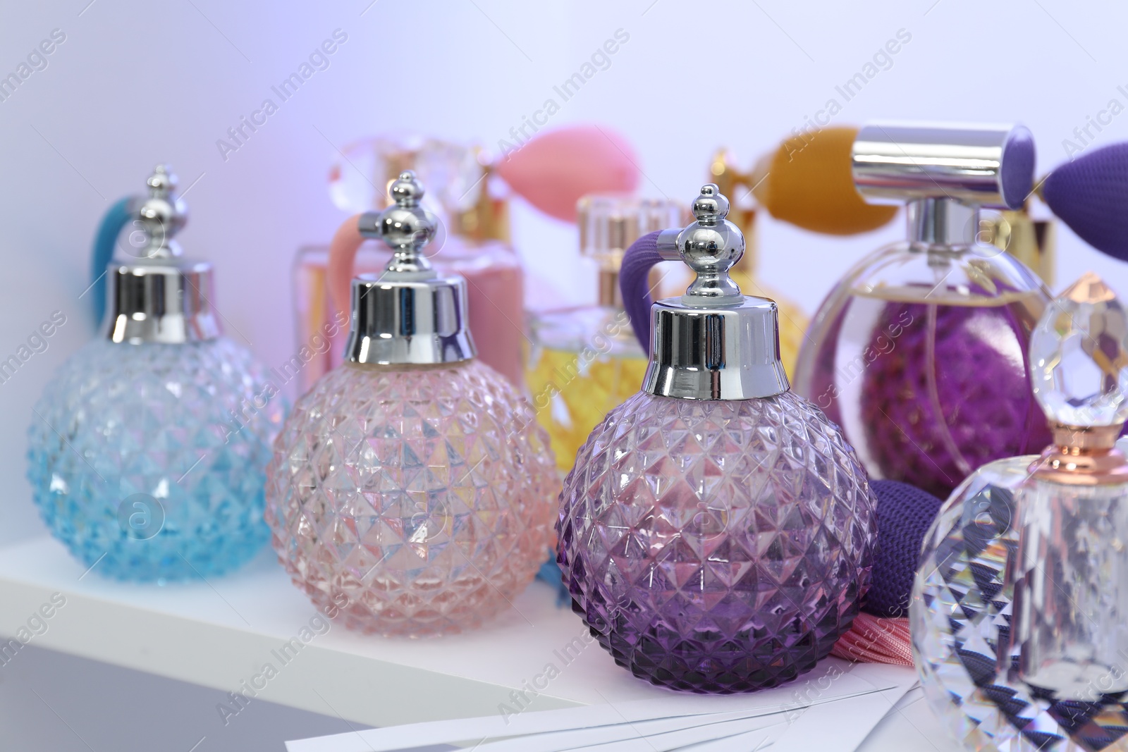 Photo of Different bottles of luxury perfume and fragrance blotters on shelf in store, closeup