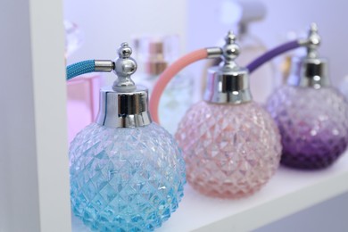 Photo of Different bottles of luxury perfume on shelf in store, closeup