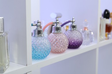 Photo of Different bottles of luxury perfume on shelf in store, closeup