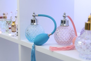 Photo of Different bottles of luxury perfume on shelf in store, closeup