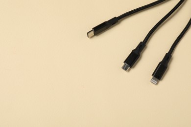 Photo of Black triple charge cable on beige background, above view. Space for text