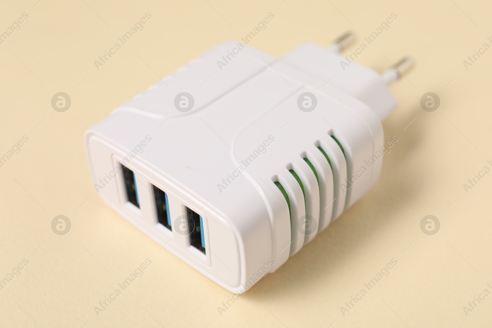 Photo of USB power adapter (charger) on beige background, closeup