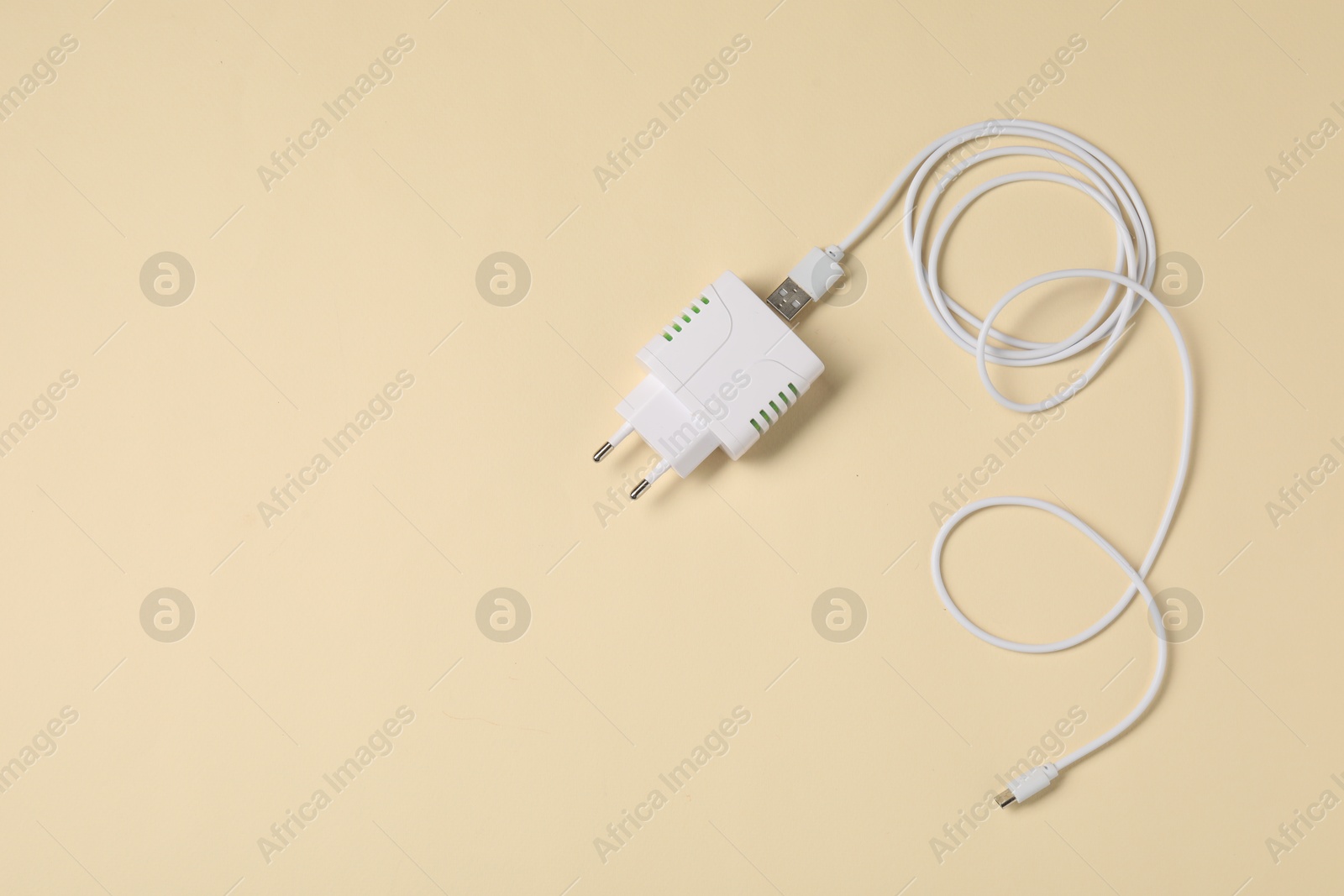 Photo of USB power adapter and charge cable on beige background, flat lay. Space for text