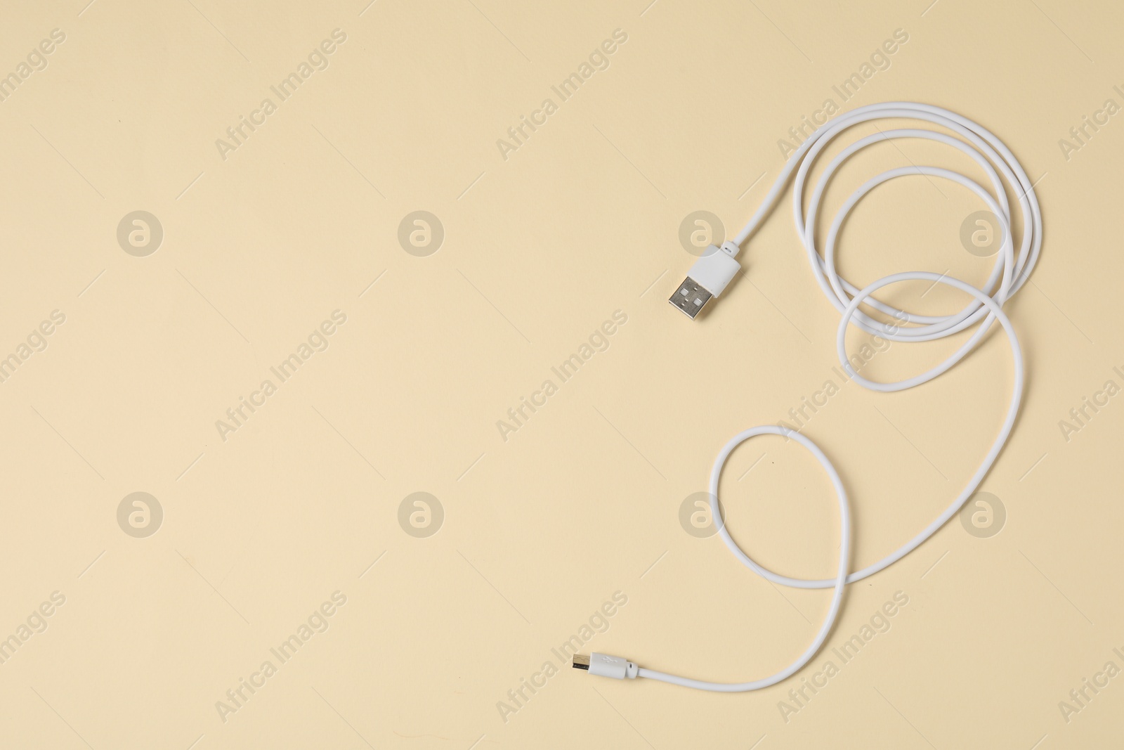 Photo of One USB charge cable on beige background, top view. Space for text