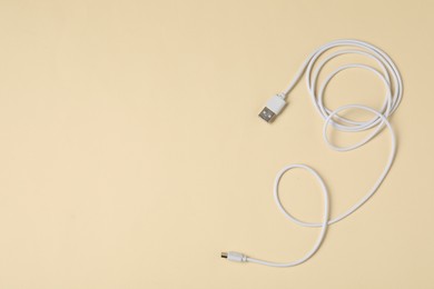 Photo of One USB charge cable on beige background, top view. Space for text