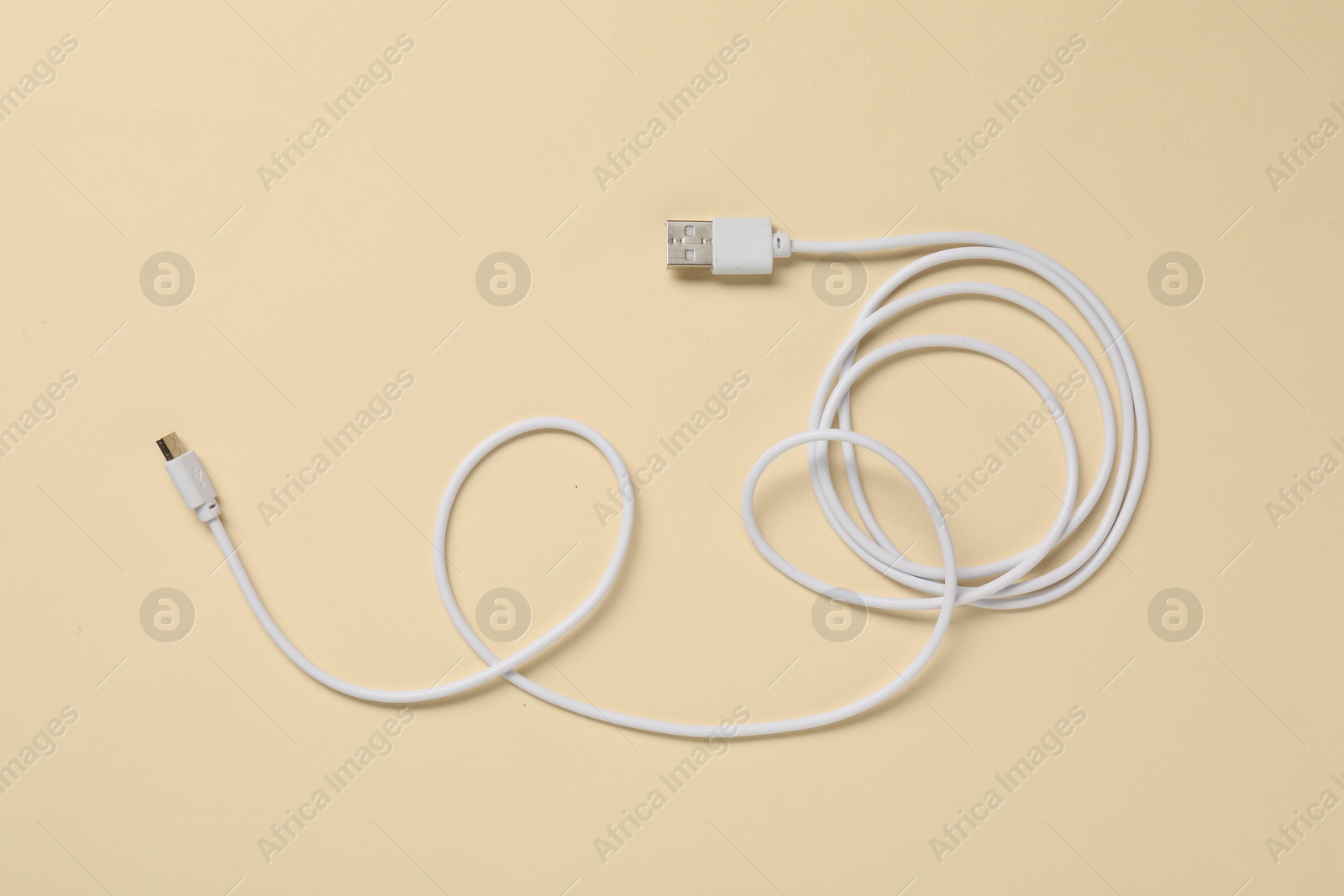 Photo of One USB charge cable on beige background, top view