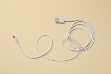 Photo of One USB charge cable on beige background, top view