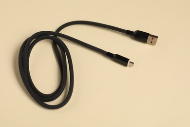 Photo of One USB charge cable on beige background, top view