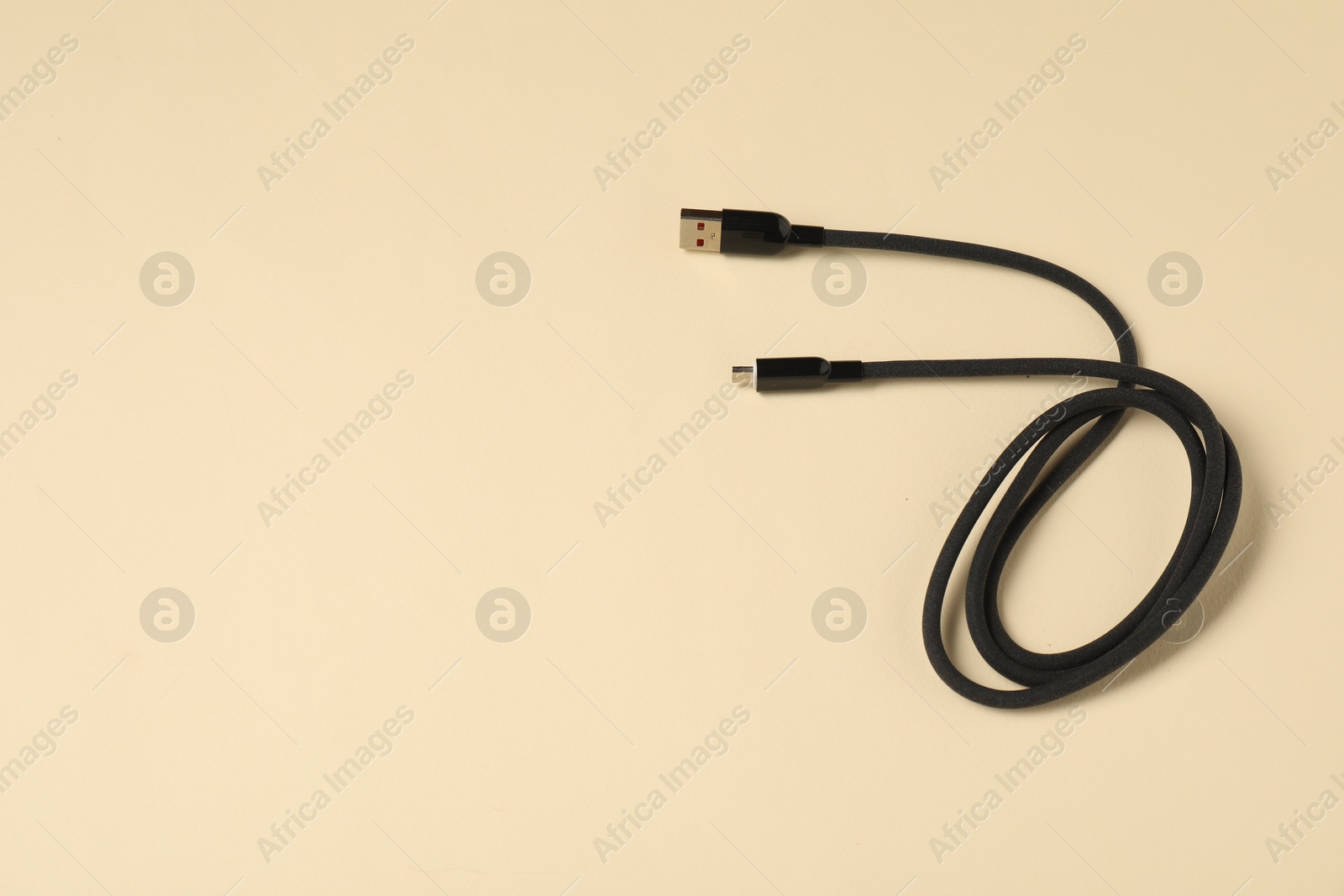 Photo of One USB charge cable on beige background, top view. Space for text