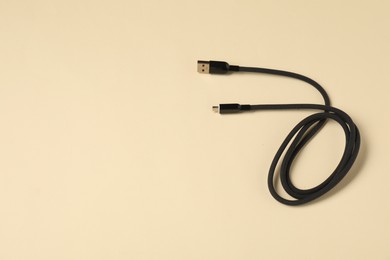 Photo of One USB charge cable on beige background, top view. Space for text