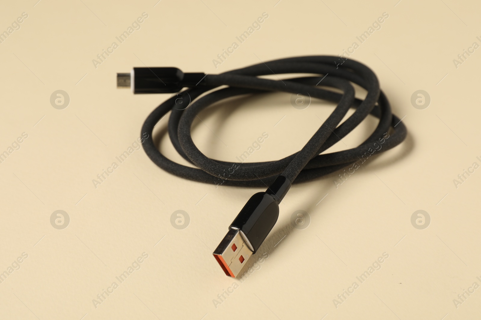 Photo of One USB charge cable on beige background, closeup