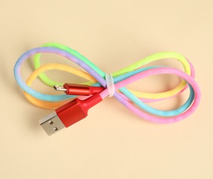 Photo of One USB charge cable on beige background, above view