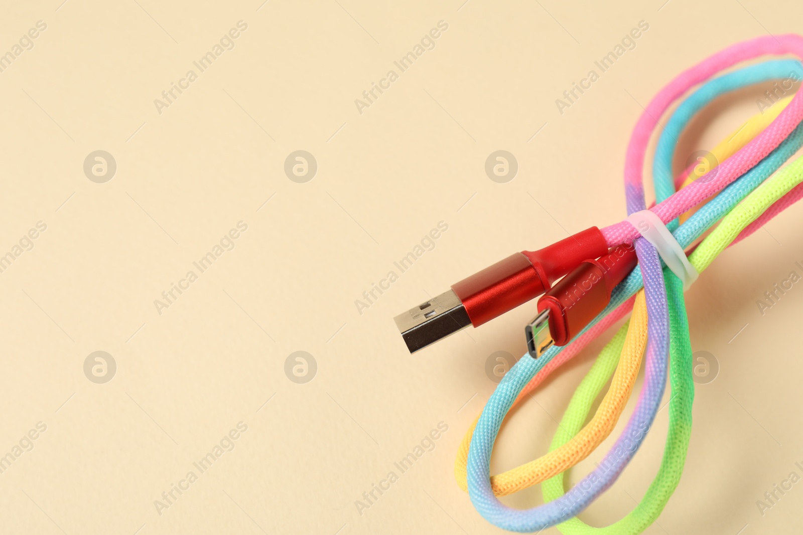 Photo of One USB charge cable on beige background, closeup. Space for text