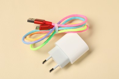 Photo of USB power adapter and charge cable on beige background, above view