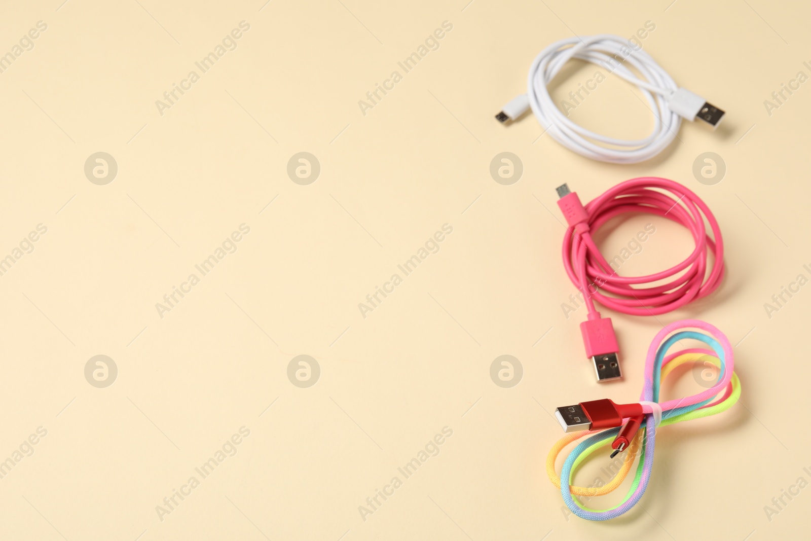 Photo of USB charge cables on beige background, above view. Space for text