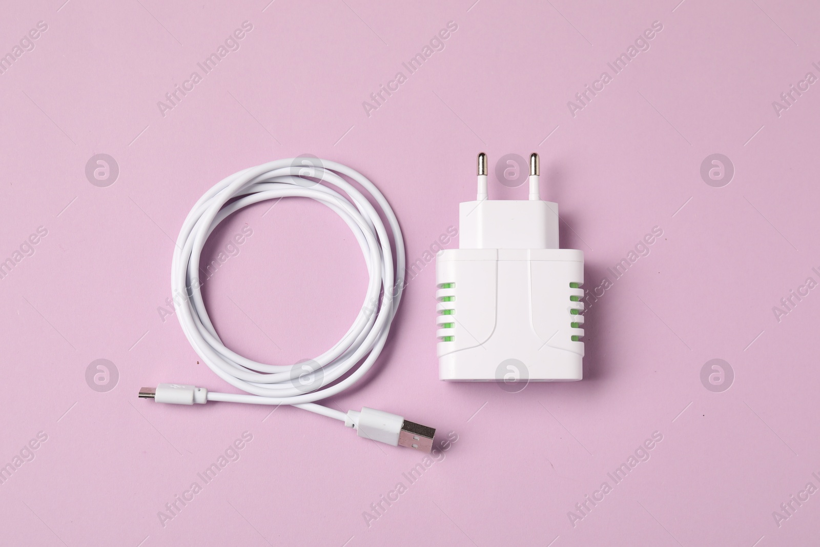 Photo of USB power adapter and charge cable on pink background, flat lay